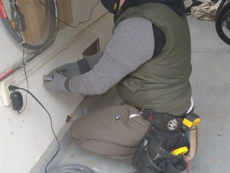 Electrician performing outlet wiring in a Brighton garage